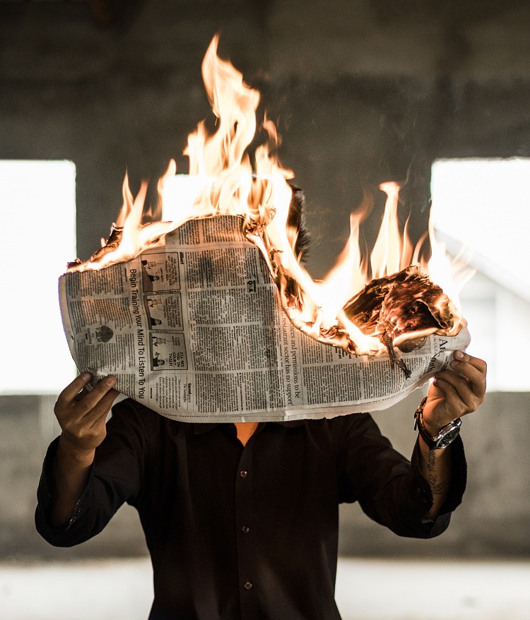person med brinnande tidning, symboliserar heta nyheter.